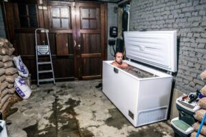 homme prenant un bain glacé dans son congélateur au garage